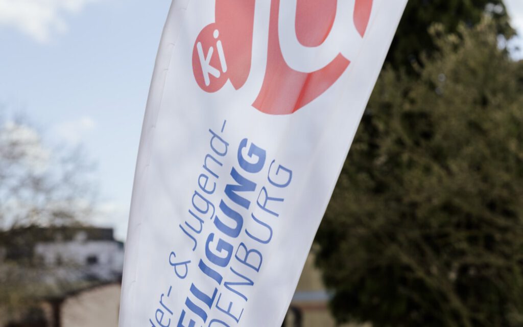Beachflag mit dem Logo „Kinder- und Jugendbeteiligung Brandenburg“ im Außenbereich